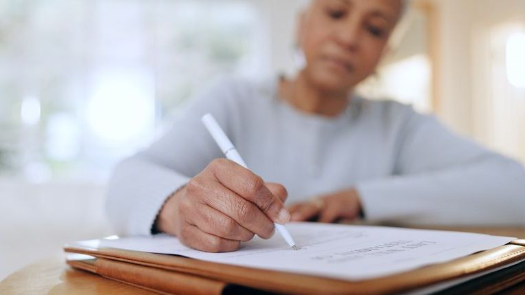 A woman fills out paperwork to enroll in her workplace retirement plan.